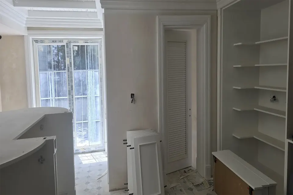 Built-in shelves, louvred door and curved white counter during installation