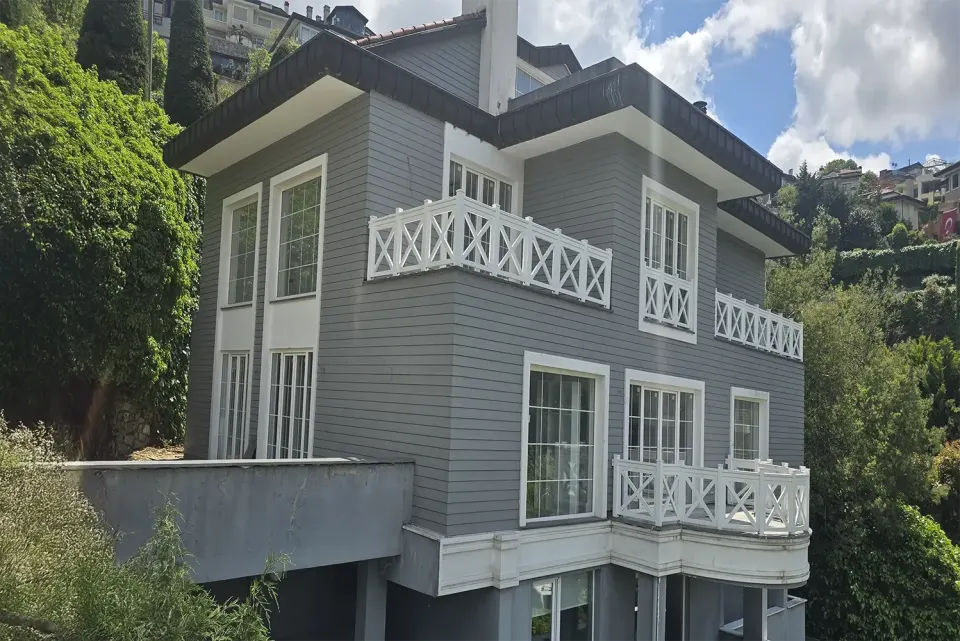 Villa facade with grey horizontal siding and white cross-braced balustrades