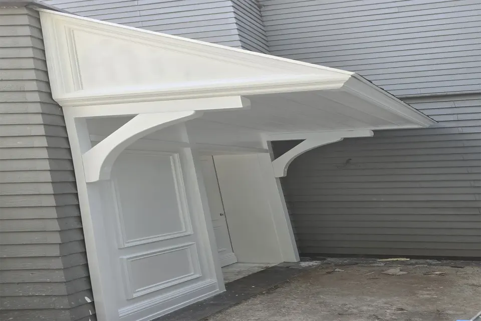 White entrance canopy with curved brackets and panelled side wall on grey siding