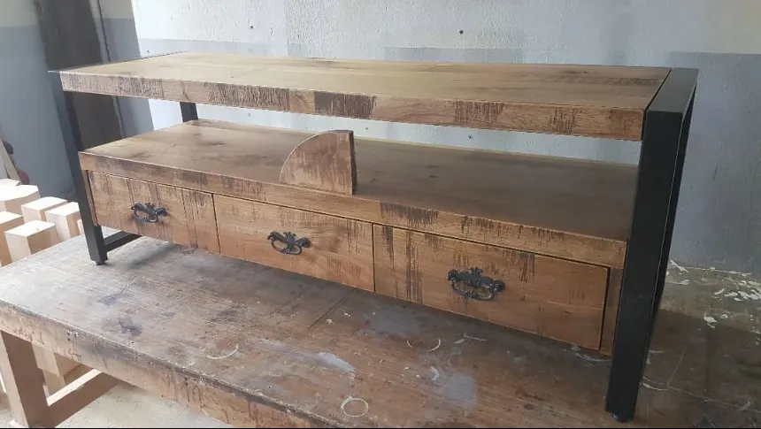 Rustic three-drawer wooden TV unit on a black metal frame in the production workshop