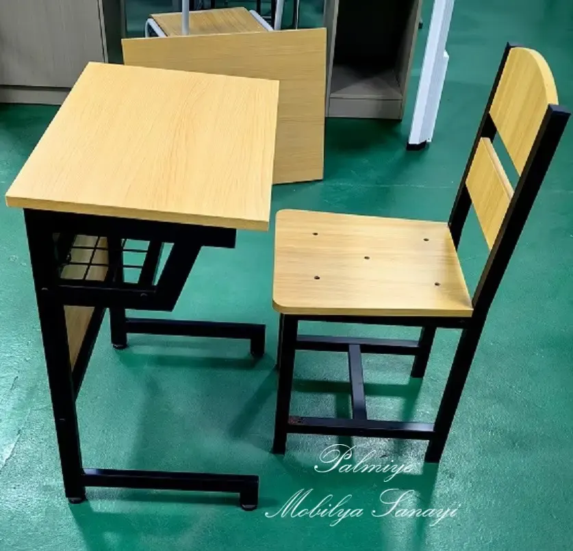 Single school desk and chair with wood-tone top and black metal frame on a green floor