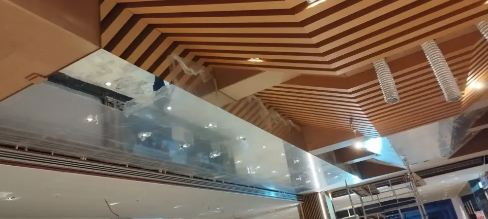 Protective film on a mirrored panel with flexible ducts above the wooden slatted ceiling