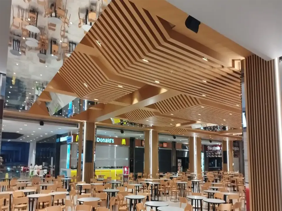 Zigzag wooden slatted ceiling framed by a slat-clad column at the edge of the food court