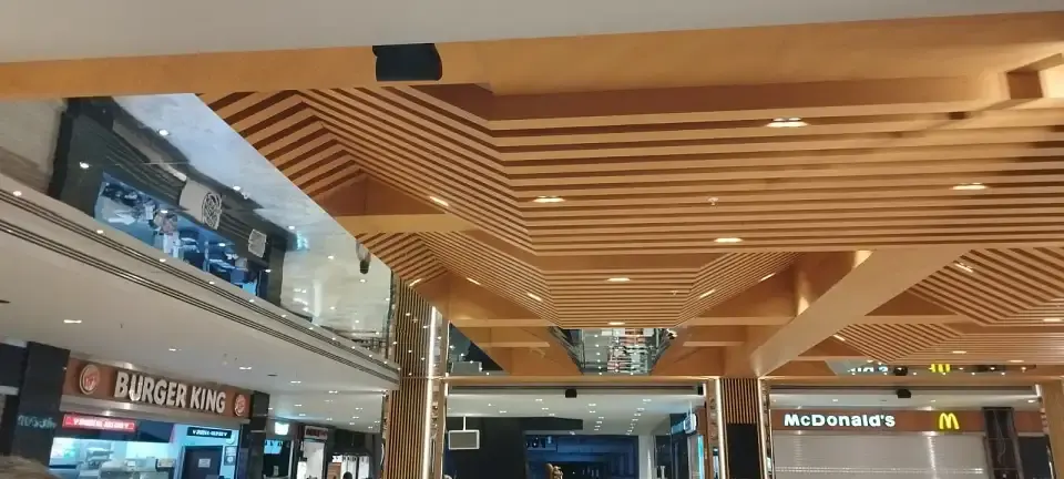 Angular timber slat ceiling over a food court, featured in the hotel furniture Turkey article