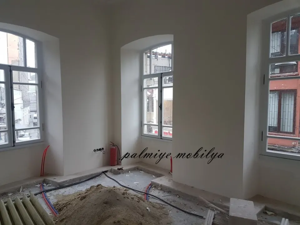 Historic building room under refit with arched windows, pipes and sand