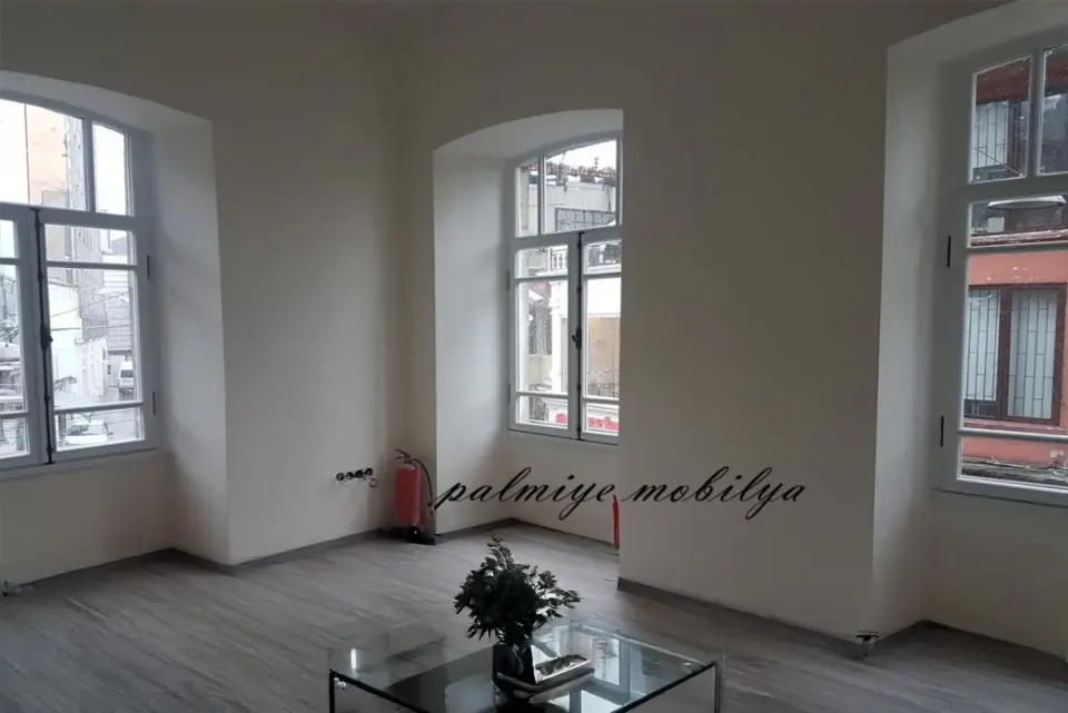 High-ceilinged room in a historic building with arched windows and a glass coffee table