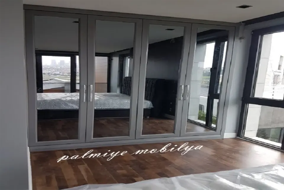 Grey-framed mirrored wardrobe doors reflecting the bedroom and its bed