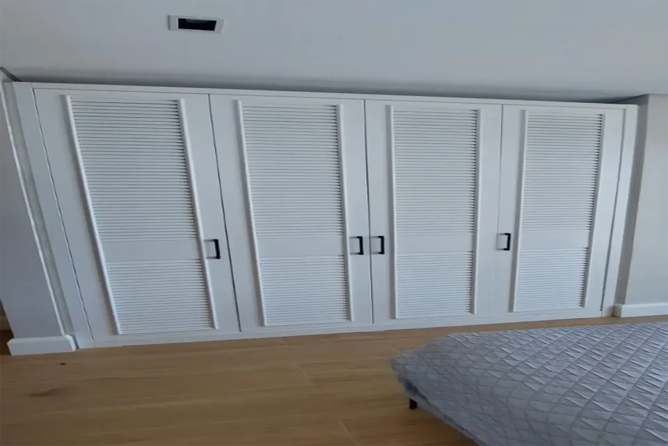 Four-door louvred wardrobe fitted opposite the bed in a villa bedroom