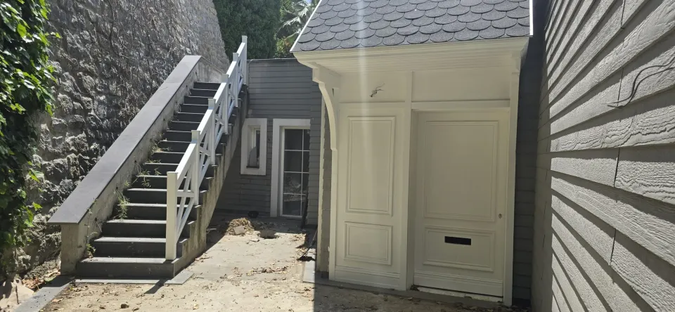 Villa rear courtyard with stone wall stairs and a white panelled double entrance door