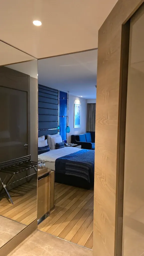 Solid wood hotel room entrance with veneer wall panel, blue headboard and plank floor