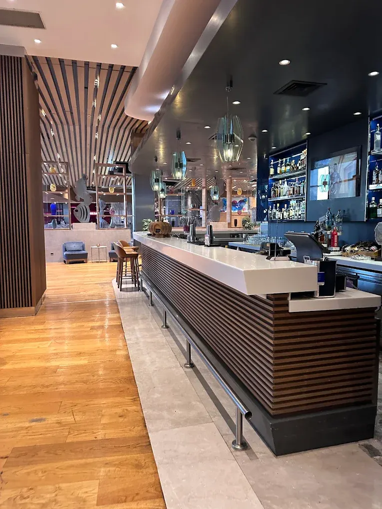 Luxury hotel bar with a wood-slat counter front, white top and slatted ceiling